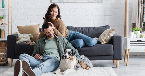 Woman, man and dog posing for a photo in a living room.