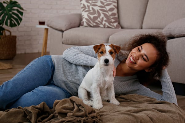 Young woman lying on the floor of her home with her small Jack Russel Terrier dog.
