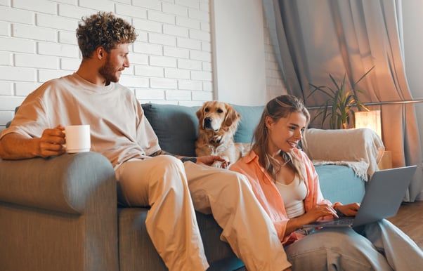 Young couple sitting together with their dog on a sofa.