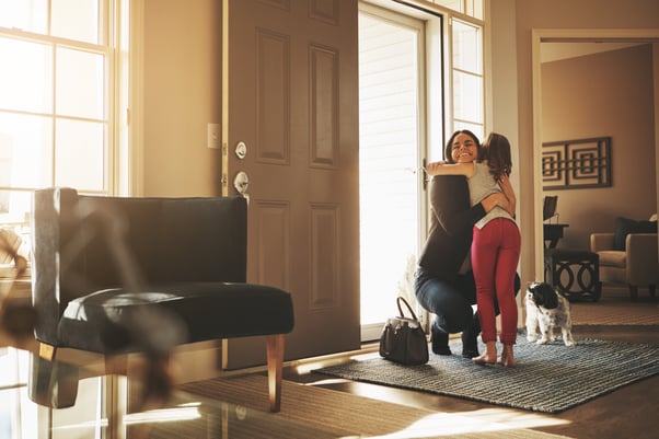 Mother and daughter greeting by the front door with their dog.