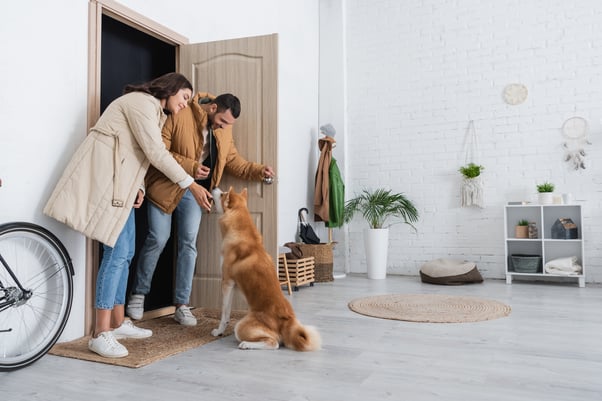 Happy dog greeting a couple as they arrive through the front door.