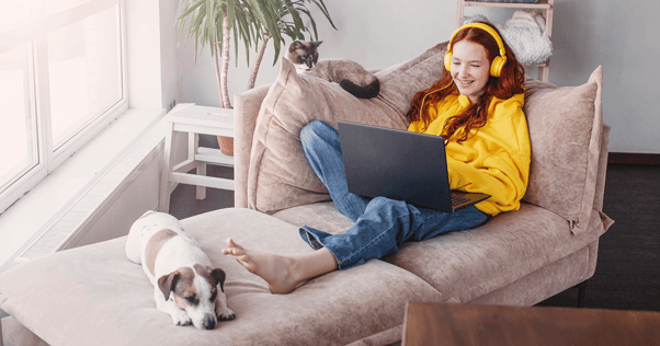 Woman relaxing on a sofa with a cat and dog.