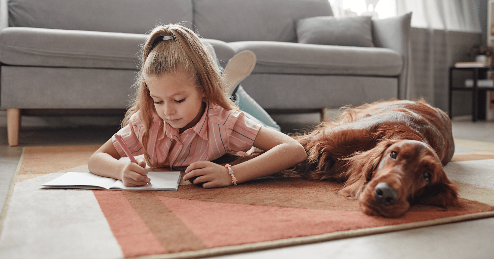 red setter and small girl laying on rug